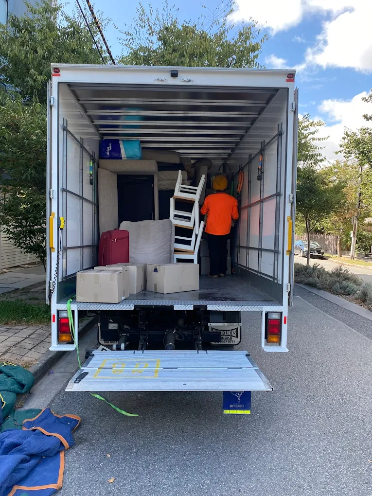 Big Stuff Movers crew loading furniture, boxes, and household items into a moving truck on a residential street.