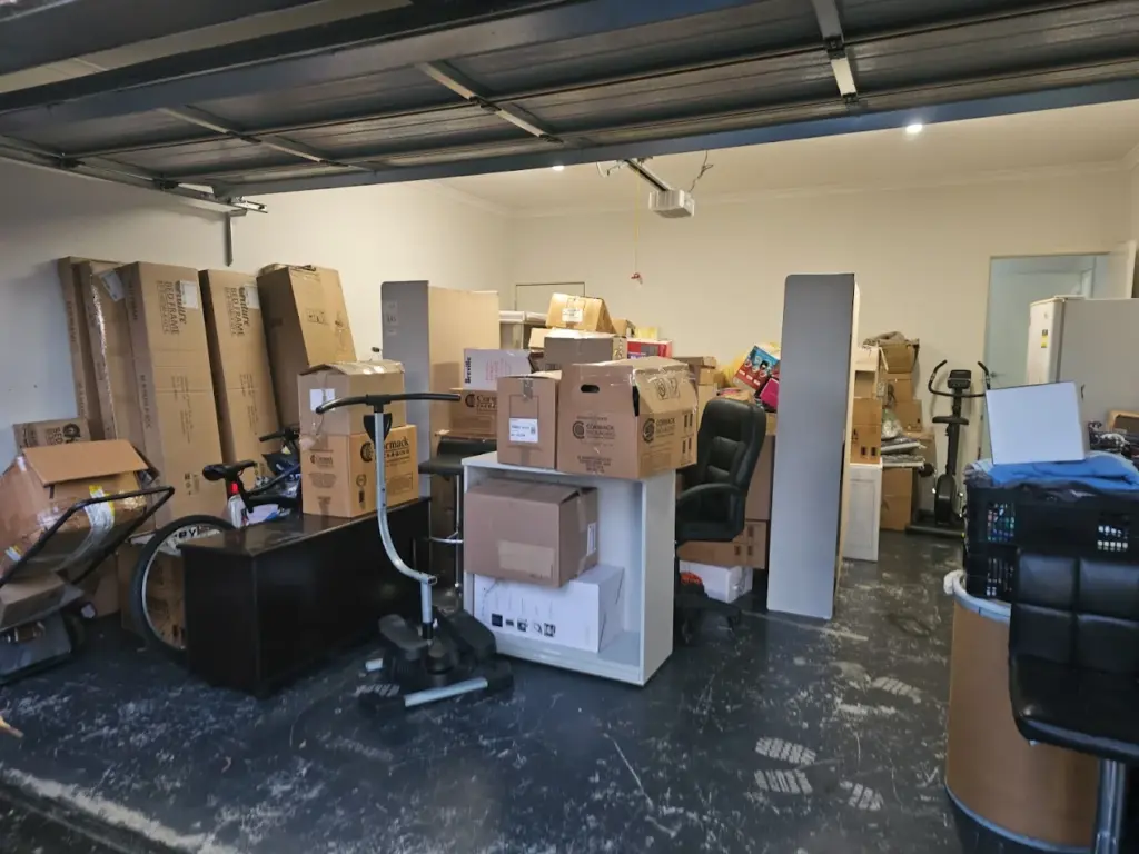 Garage packed with moving boxes, furniture, exercise equipment, and household items ready for Big Stuff Movers to organise and relocate.