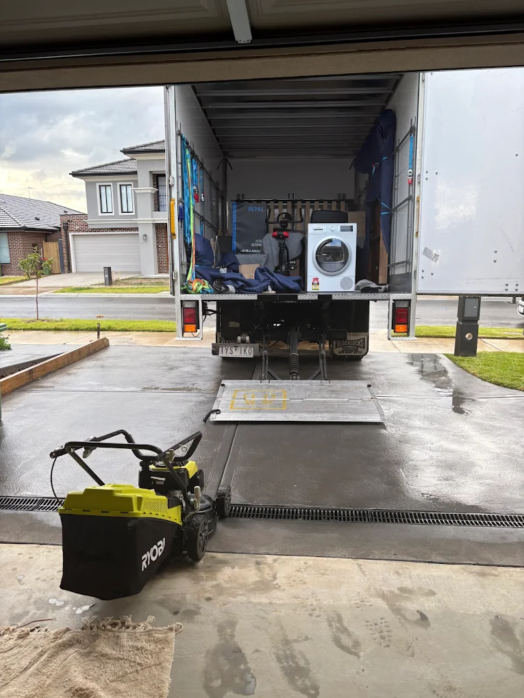 Moving truck being loaded with household items like a washing machine — furniture loading, house moving, big stuff movers.
